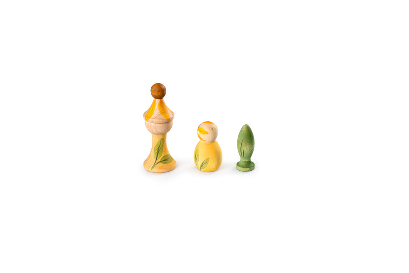 The image shows three wooden figurines with unique shapes and colors. The first figurine on the left is tall with a rounded top and has a yellow and natural wood color with green leaf patterns. The middle figurine is shorter and rounder, predominantly yellow with green leaf patterns. The third figurine on the right is the smallest, green in color, and shaped like a pawn from a chess set.