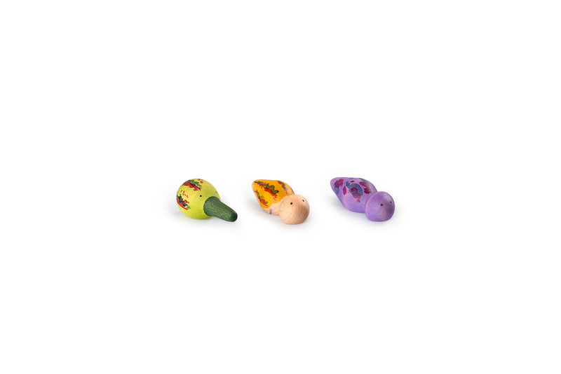 The image shows three small, colorful wooden bird figurines. The first bird is green with red and yellow patterns, the second bird is yellow with red and orange patterns, and the third bird is purple with red and blue patterns. These figurines are vibrant and uniquely designed, making them visually appealing and suitable for decoration or as toys.