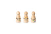 The image shows three wooden peg dolls with round heads and cylindrical bodies. Each doll has colorful decorations: green and blue dots with a ladder and house drawing on the first, orange and yellow dots with a house and tree on the second, and green, blue, and purple dots with a flower on the third. The dolls are arranged in a row and have a playful appearance.
