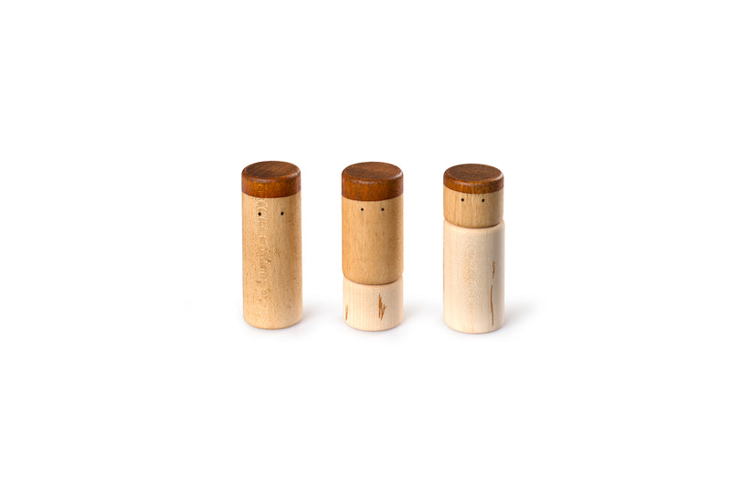 The image shows three wooden cylindrical objects with darker wooden tops. Each object has two small eyes. The objects are arranged in a row against a white background.