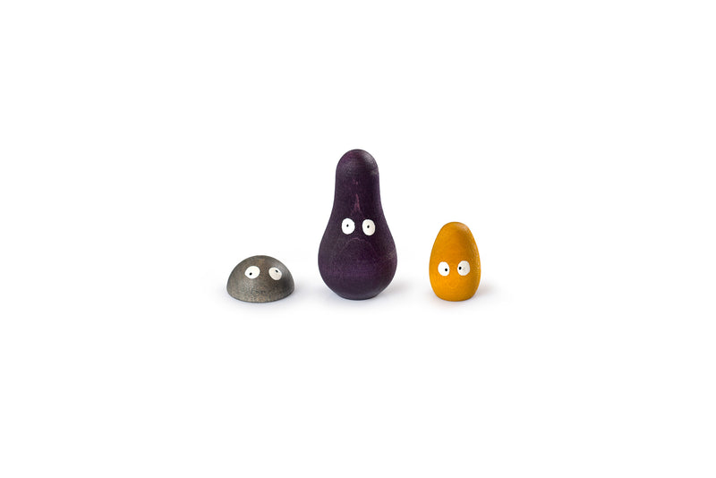 The image shows three small, rounded objects with eyes painted on them. The objects are of different shapes and colors: the left one is gray and dome-shaped, the middle one is purple and elongated, and the right one is orange and egg-shaped. The eyes on each object give them a whimsical and animated appearance, making them look like playful characters.