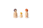 The image shows three wooden peg dolls of varying sizes. The dolls are painted with different colored dots and patterns on their heads and bodies. The largest doll on the left has purple dots and a purple pattern on its head. The smallest doll in the middle has yellow dots and a yellow pattern on its head. The medium-sized doll on the right has red dots and a red pattern on its head. The dolls are arranged in a line, with the smallest in the center.