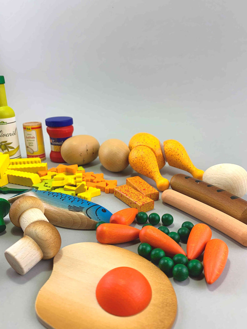 Woodberry Erzi Assorted Cooking Enjoyment for Play Kitchen. Play Food Wooden Toy Set.  This photo included a large sunny side up egg at the front and 5 carrots, some peas, two crimini mushrooms, one fish, a hotdog, a sausage, an hard boiled egg, a chicken, two potatoes, pasta sause, pasta, french fries and olive oil