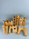 Woodberry Bauspiel castle blocks 10 piece set arranged to show the different pieces, including two unique castle gates, a pair of stair, two pairs of towers and a pair of castle walls. 