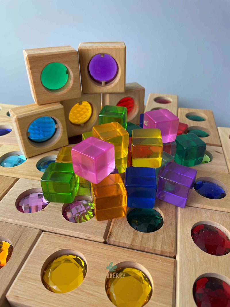 Up close image of Bauspiel combination set standing upright. Includes 20 wooden colour street blocks, 20 acrylic lucent cubes, 5 gemmed window blocks and tray. Photo shows window blocks stacked with lucent cubes randomly placed in front, all on top of colour street blocks. 