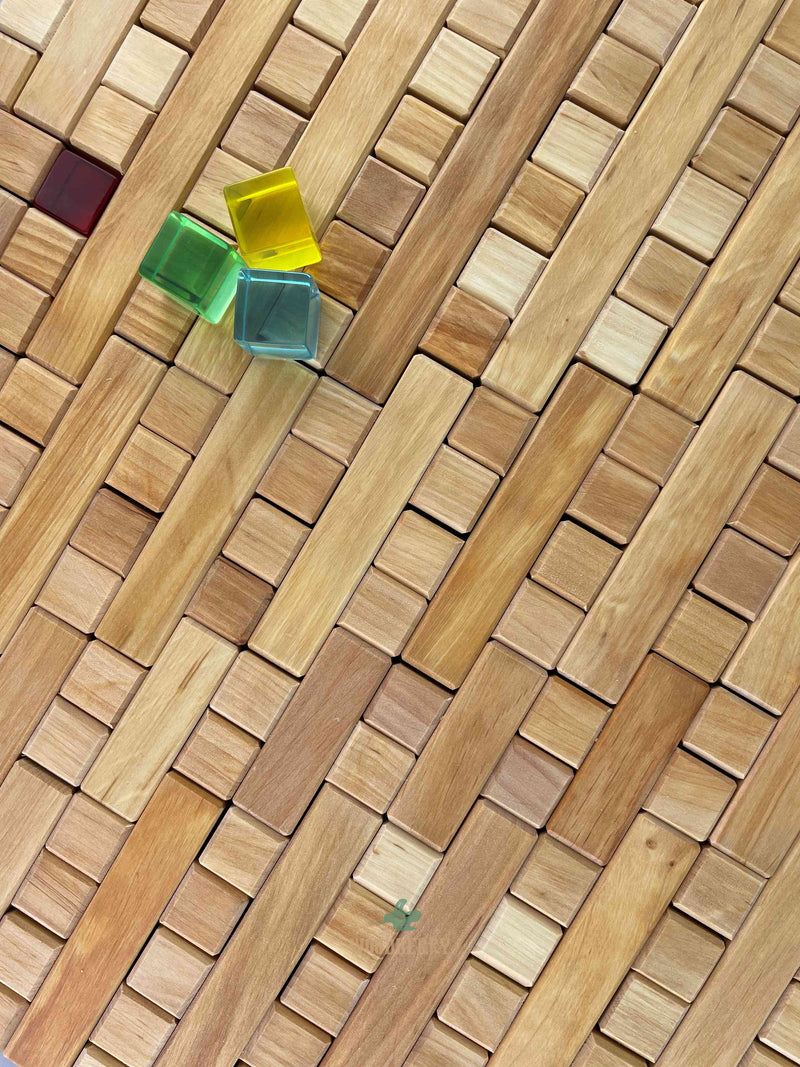 Top-down photo of some lucent cubes from Bauspiel on an arrangement of plus blocks creating a patterned surface. 