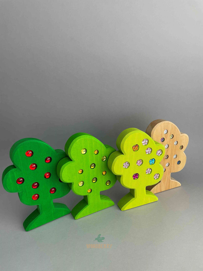Set of 4 wooden trees with gemmed fruit from Bauspiel. Standing and lined up in a row. 