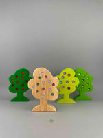 Set of 4 wooden trees with gemmed fruit from Bauspiel. Standing and lined up in a row. 