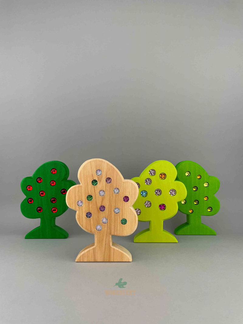 Set of 4 wooden trees with gemmed fruit from Bauspiel. Standing and lined up in a row. 