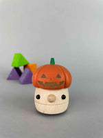 Halloween wooden toy. Mushroom Ramp walker with a orange pumpkin Jack'O'Lantern hat with purple, green and orange wooden building blocks in the background
