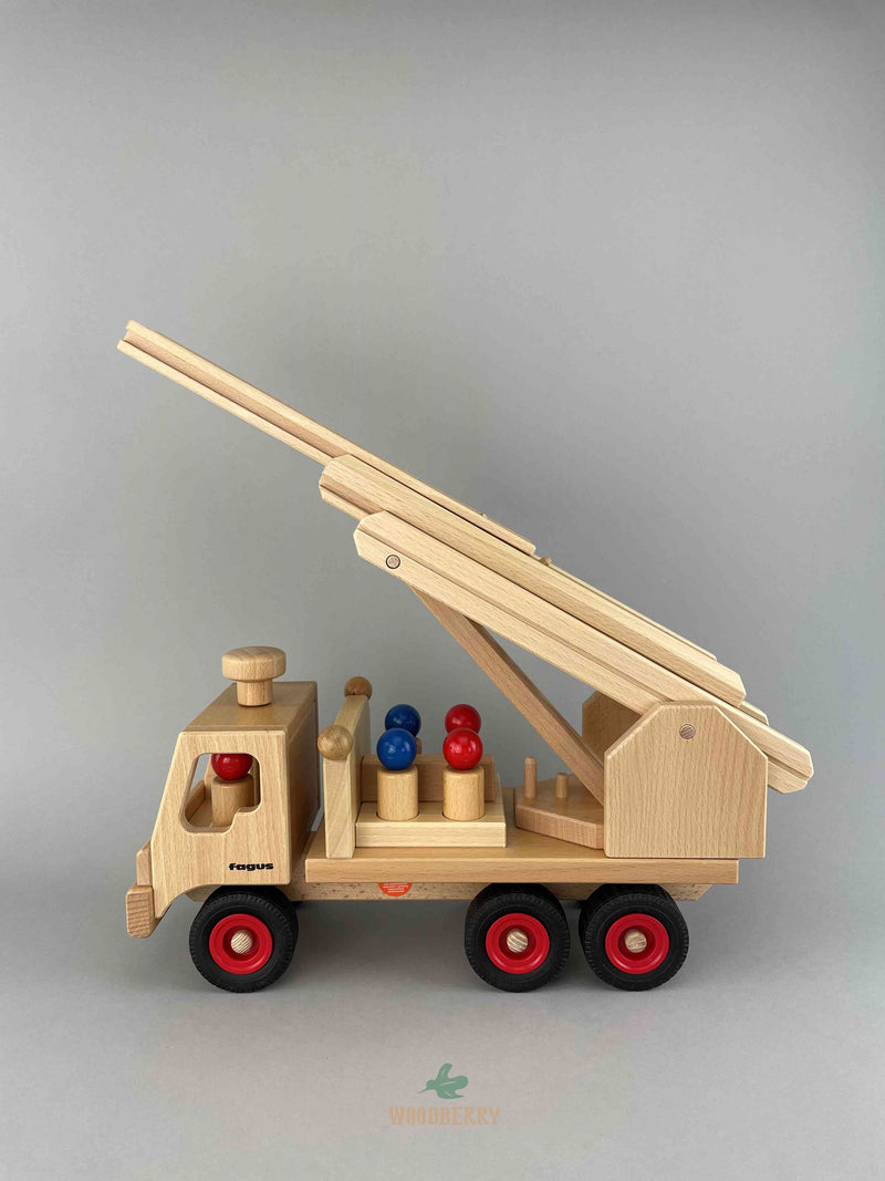A side view of Fagus wooden Fire engine with the arm lifted at a 40 degree angle. Six red and blue peg doll are inside of the fire engine - two at the front and four at the back.