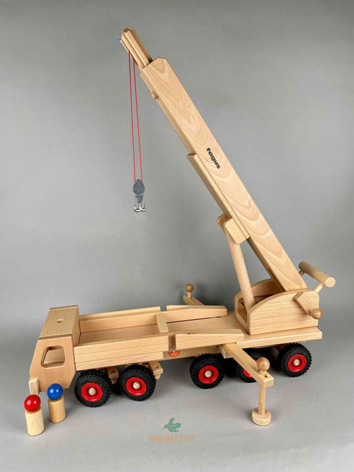 Woodberry Fagus Wooden Mobile Tower Crane wooden toy side view angle with raised arm, lowered hook and extended outriggers. Includes two peg people.  