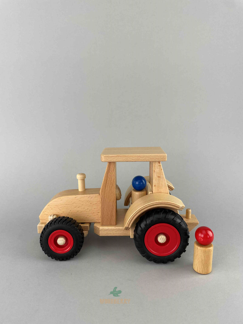 Side view of Fagus modern tractor wooden toy. One blue peg doll is sitting in the vehicle and one red peg doll is standing at the back of the tractor.
