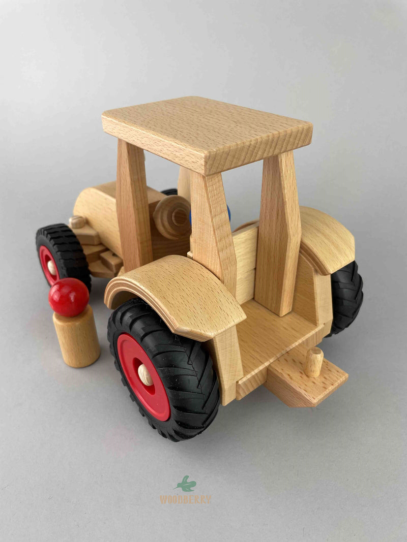 A close-up view of the back and interior of the Fagus wooden Modern Tractor toy. One red wooden peg doll is at the side of the tractor.