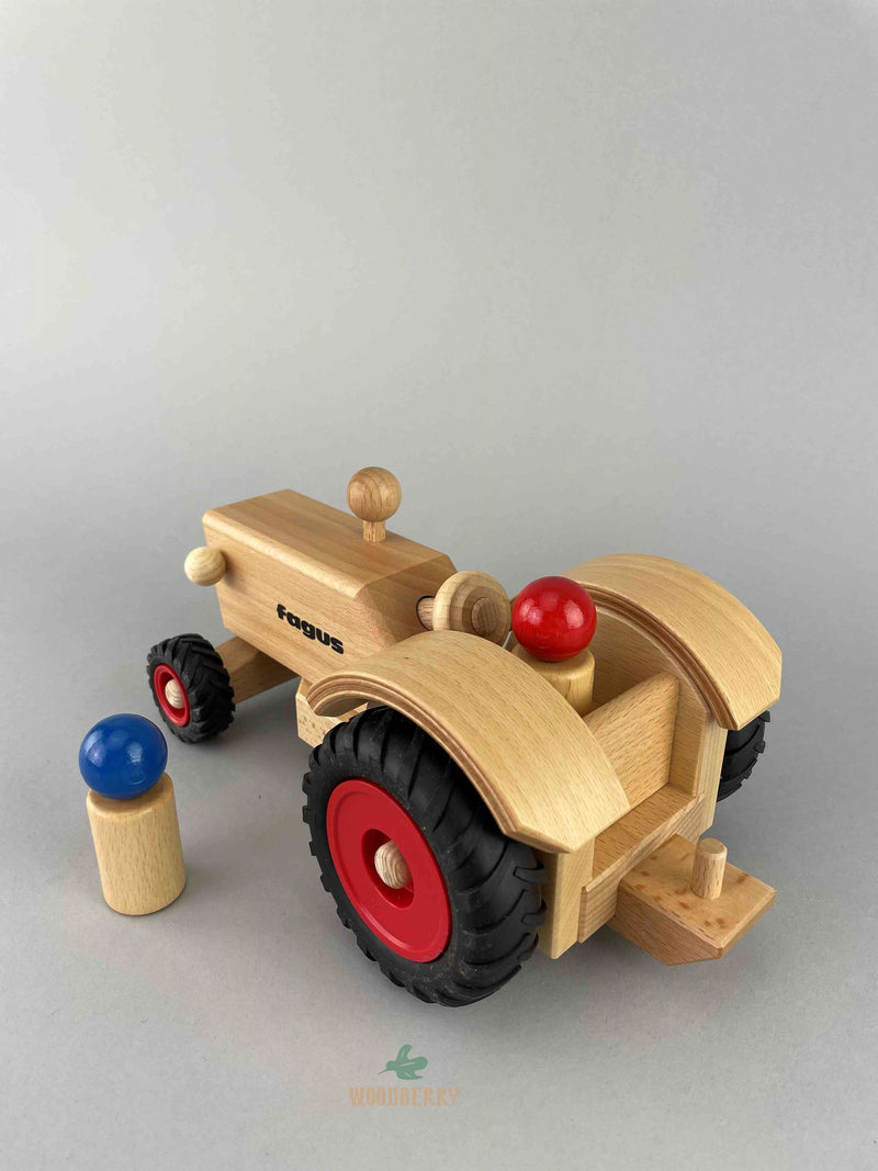 Fagus wooden toy Tractor rear view to see the back hitch dowel. The tractor is open-top with large wheels at the back and small wheels at the front. 