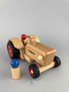 Front view of the Fagus wooden toys old-fashioned tractor. Two sets of different size rubber tires. one red peg doll sitting inside and one blue peg doll standing outside of the vehicle.
