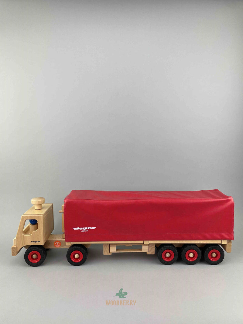 Woodberry Fagus Semi-Truck and Trailer wooden toy. Side view image of the truck with two peg people sit in the cab of the truck. 