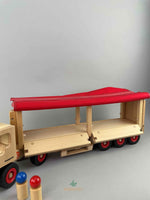 Woodberry Fagus Semi-Truck and Trailer wooden toy with tarpaulin cover raised on both sides and trailer gates lowered to show accessibility of trailer contents. Two peg people in the foreground.