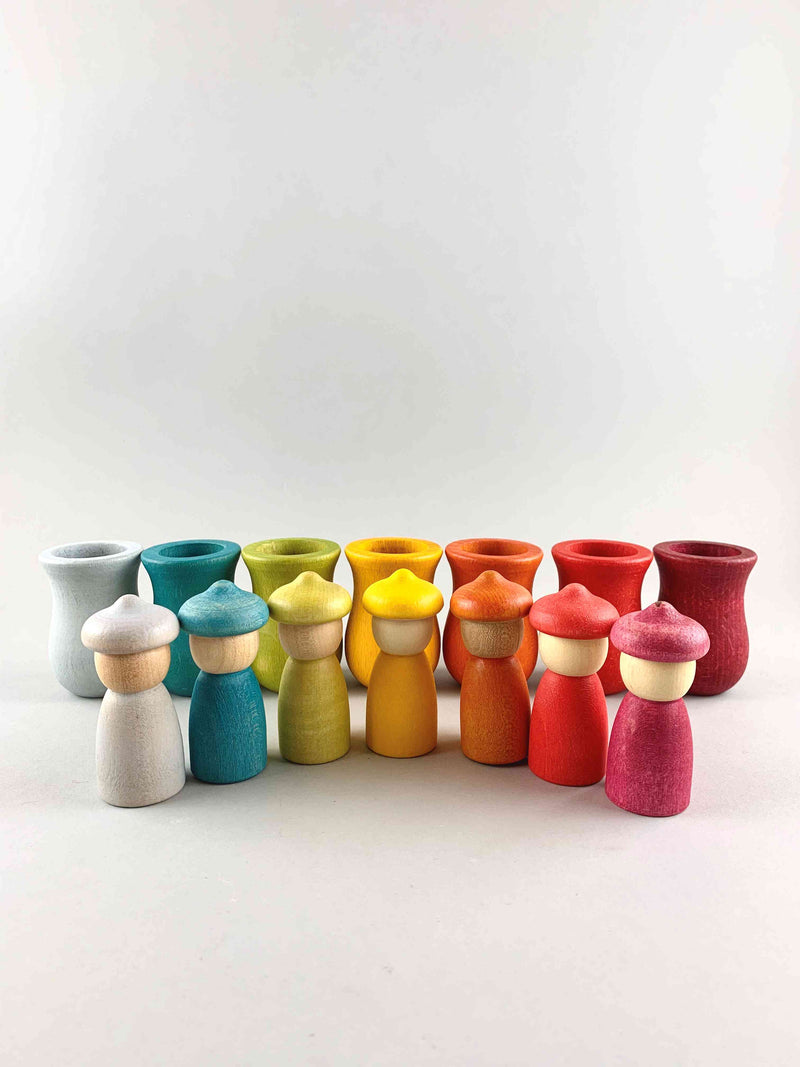 Seven rainbow color Grapat Weekly Calendar cups and Nins wooden toy figures placed in separate rows. 