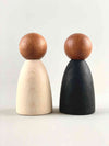 Two oversized dark wood tone Grapat Nins wooden toy figures in black and white placed adjacent to each other.