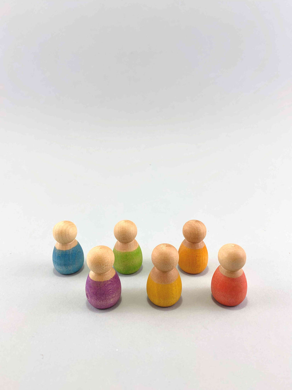 Wooden baby nins by Grapat in a half circle surrounding the upside down coconut shell e