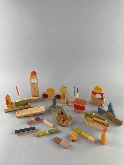 Set of Grapat 2023 Happy Place wooden blocks placed in miscellaneous shapes resembling buildings, cars and boats. 