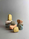 9 pieces of wooden balancing stones by Danish company minmin Copenhagen. This is a pastel set with 1 white, 2 gray, 2 baby blue, 2 peach orange, 2 soft yellow. In one stack of three stones and 2 stacks of 2 stones.