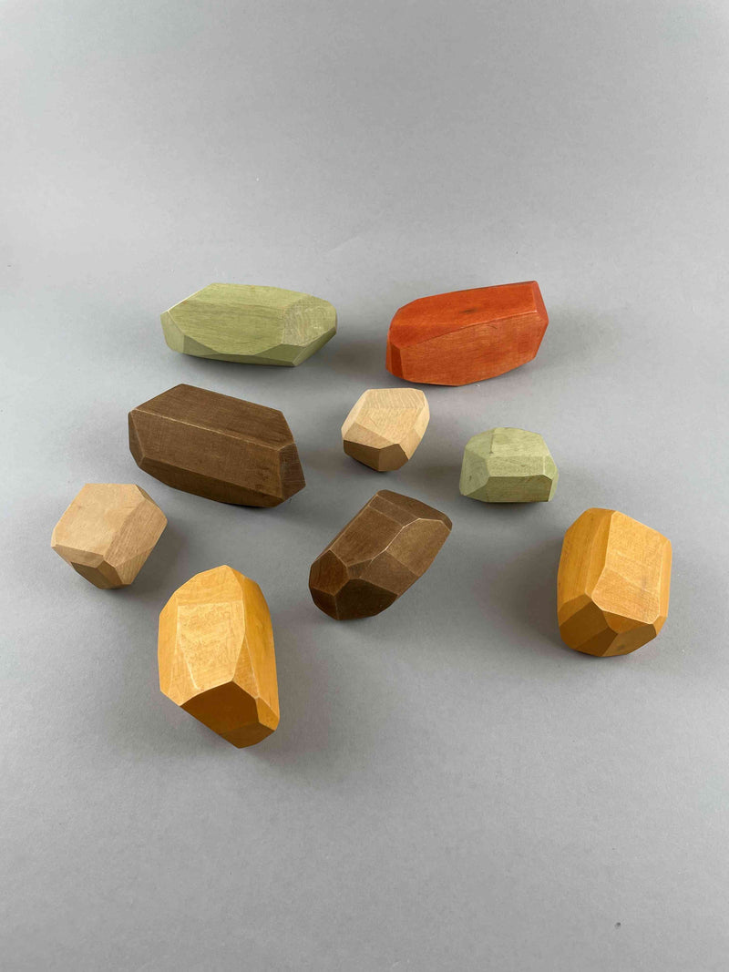 The wooden balancing stones toy by Danish maker Minmin Copenhagen. This is the earthy set with brown, beige, olive green, golden and brick red. Scattered on the surface with gray background