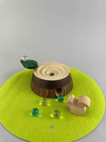 Woodberry Oak Village marble run tree stump with glass marbles and wooden squirrel figure on green felt mat.  