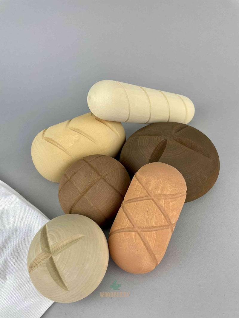 six pieces of wooden bread toy by Raduga Grez in a pile on top of the cotton draw string bag