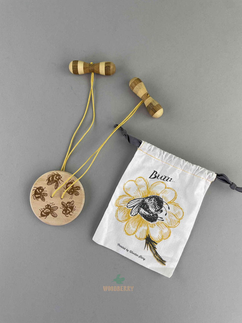 Wooden Swirling Disc. A round, 2-holes button shaped disc with bee patterns with one yellow string connected by two wooden handles. comes in a bee graphic decorated cotton string bag